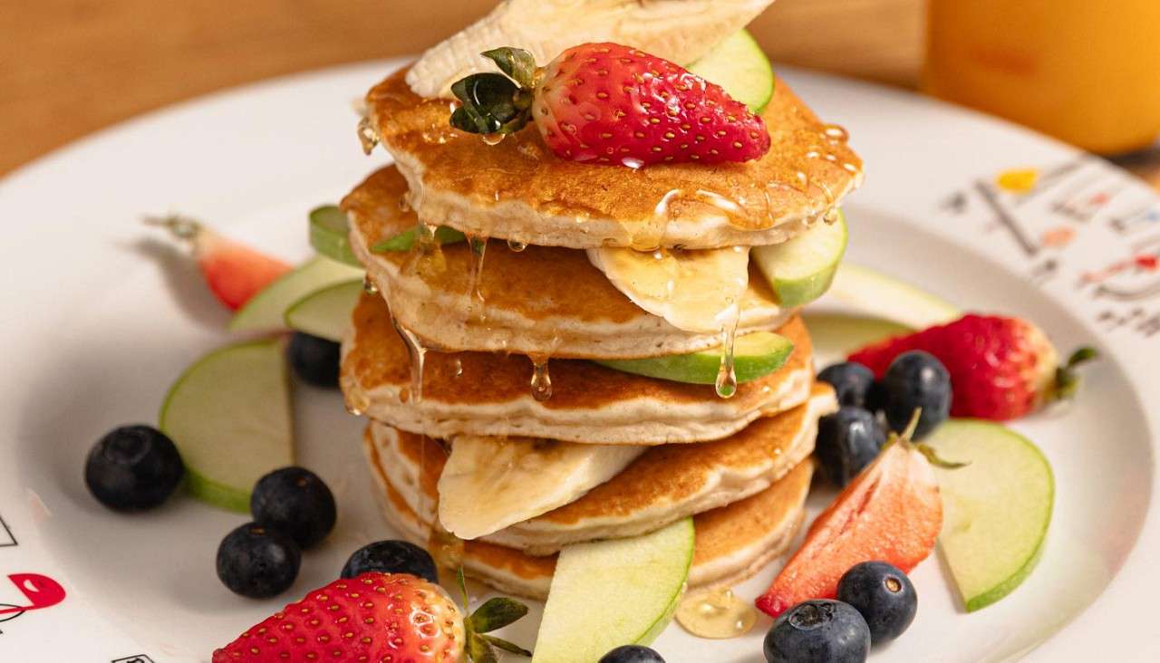 Pancakes topped with fresh fruit and a drizzle of honey.