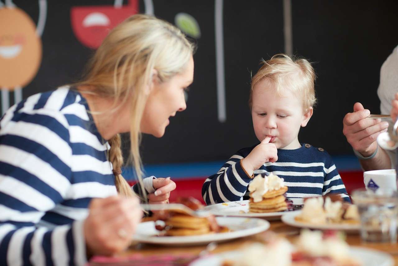Woman with a young child eating sweet treats from The Pancake House menu.