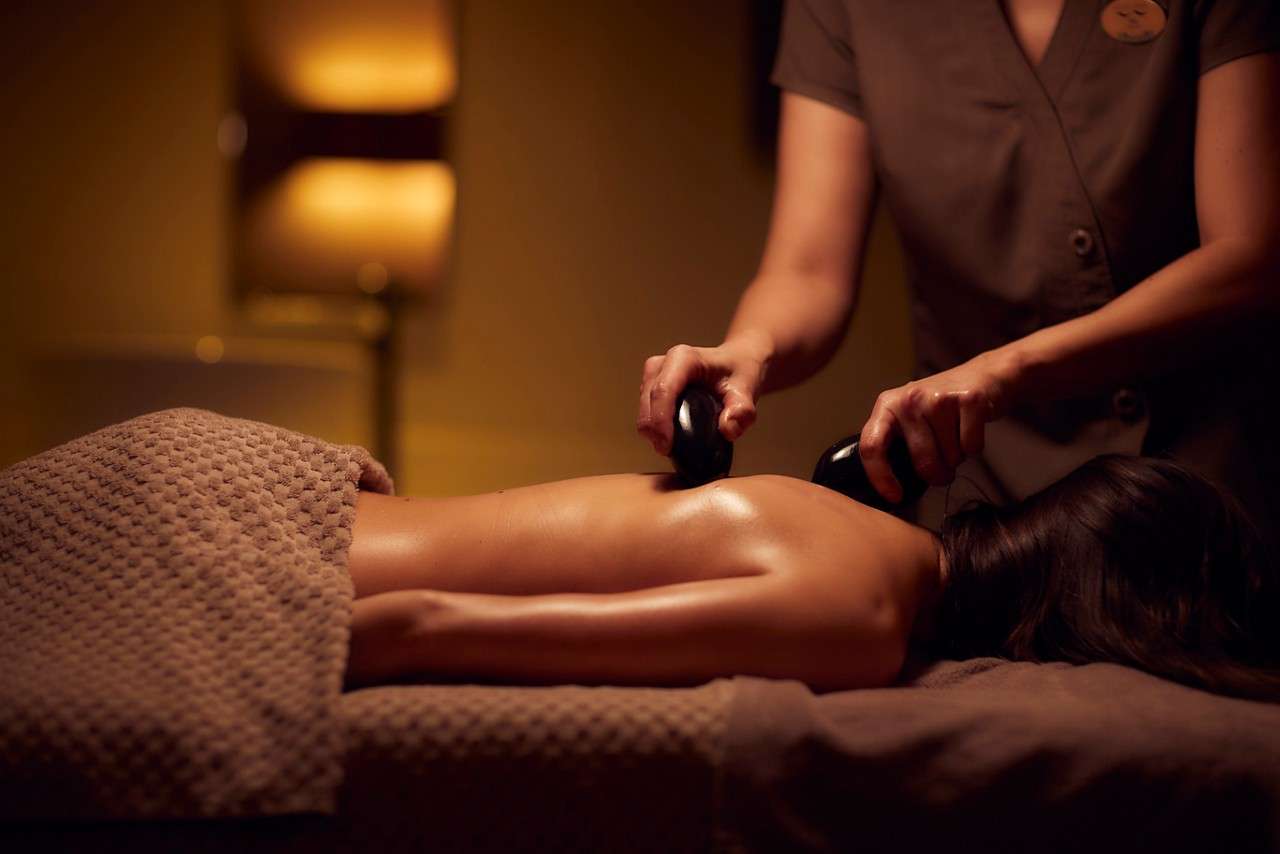 Spa therapist giving a woman a Thermabliss hot stone body massage.