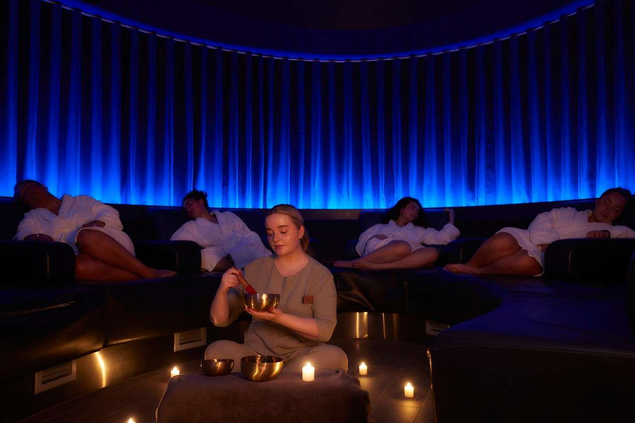 People sat in spa robes relaxing in dark lighting