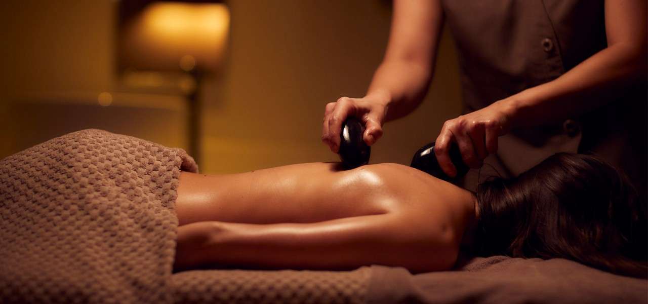 woman laid receiving  back massage with stones 