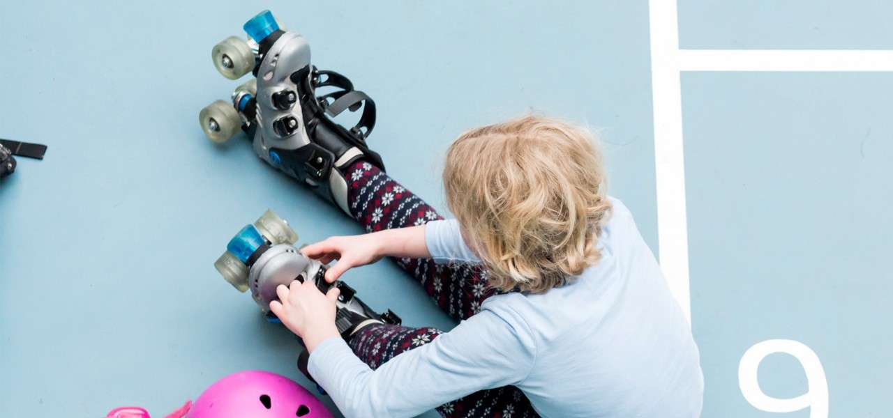 A child putting on a pair of roller skates. 