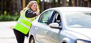 A secuirity worker directing a car