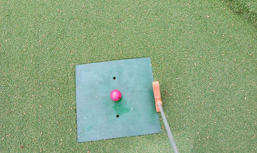 A golf ball on the green with a club next to it