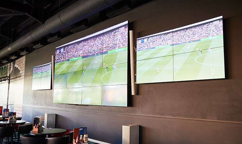 Sports being shown on a large screen on the wall
