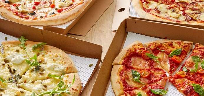 Freshly made pizzas in takeaway boxes.