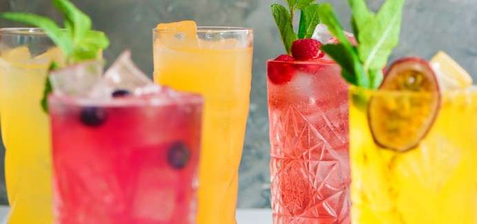 Colourful soft drinks topped with fresh fruit.