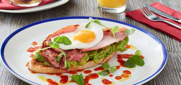Avocado on toast topped with bacon and fried egg.