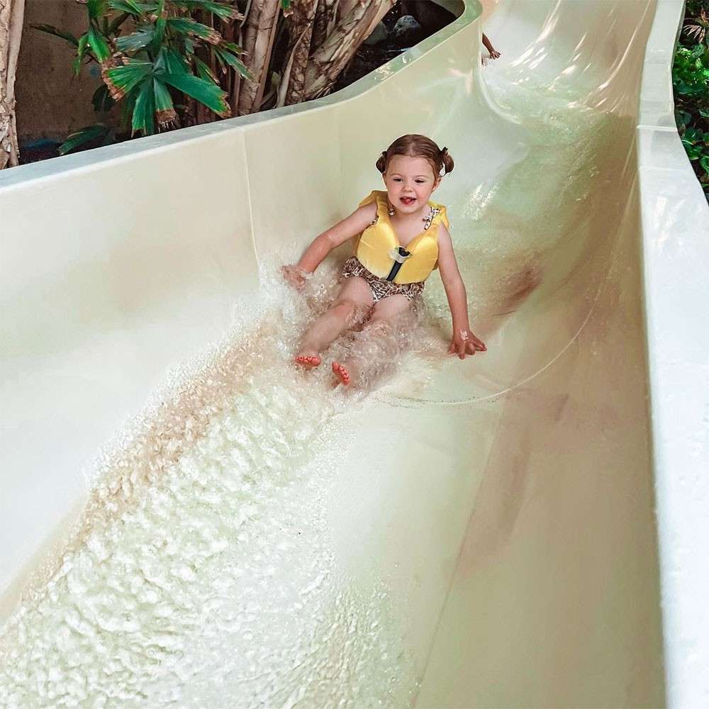 A little girl sliding down a slide in the Subtropical Swimming Paradise.