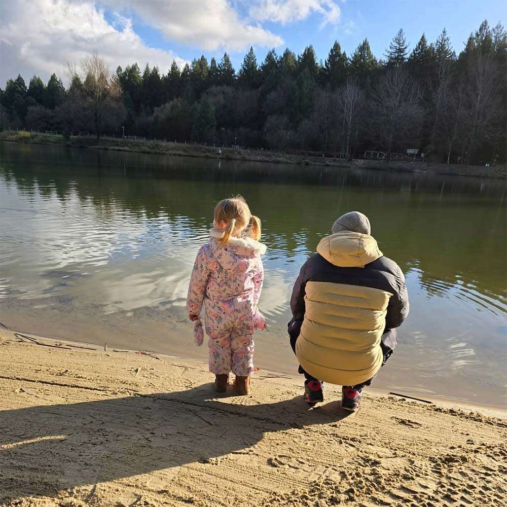 A parent and their child stood next to the lake.