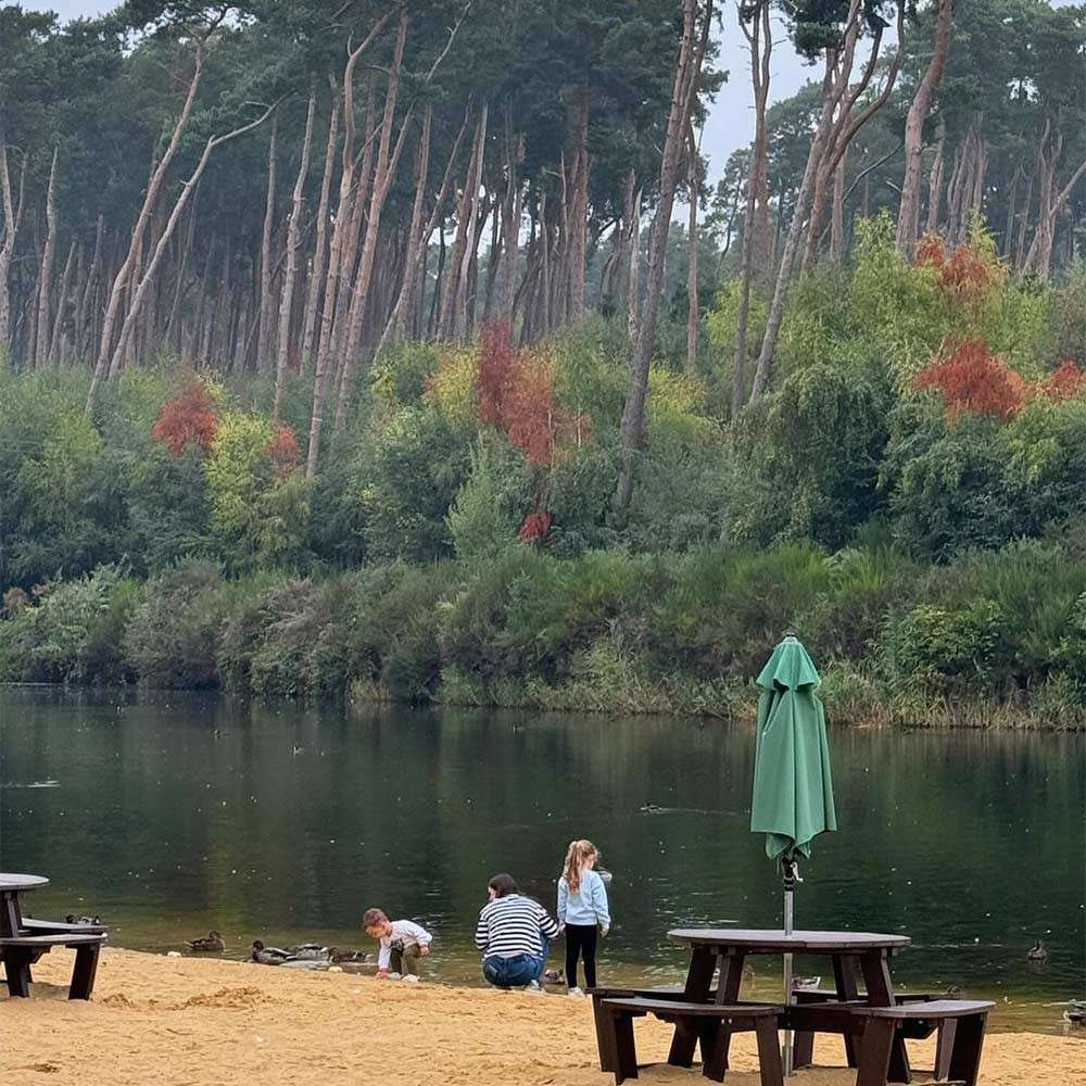 A family stood next to the lake on the beach.