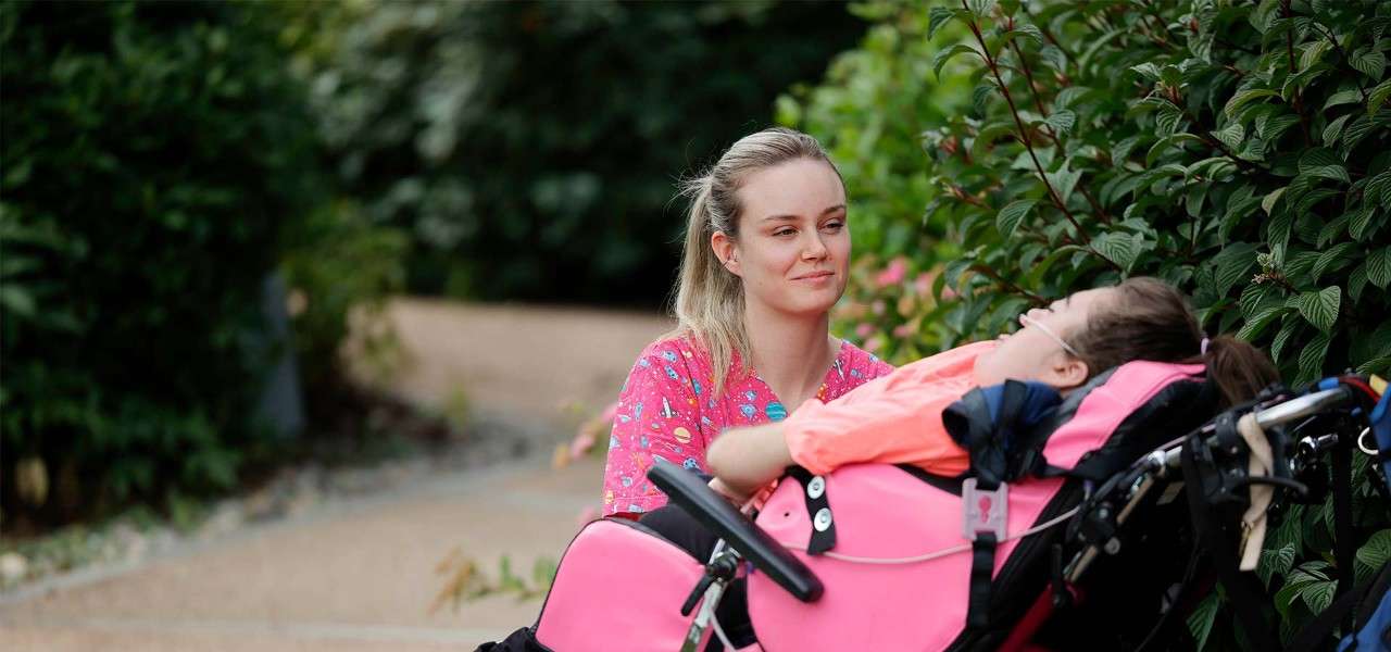 A young female helper and a young girl in a motorised wheelchair