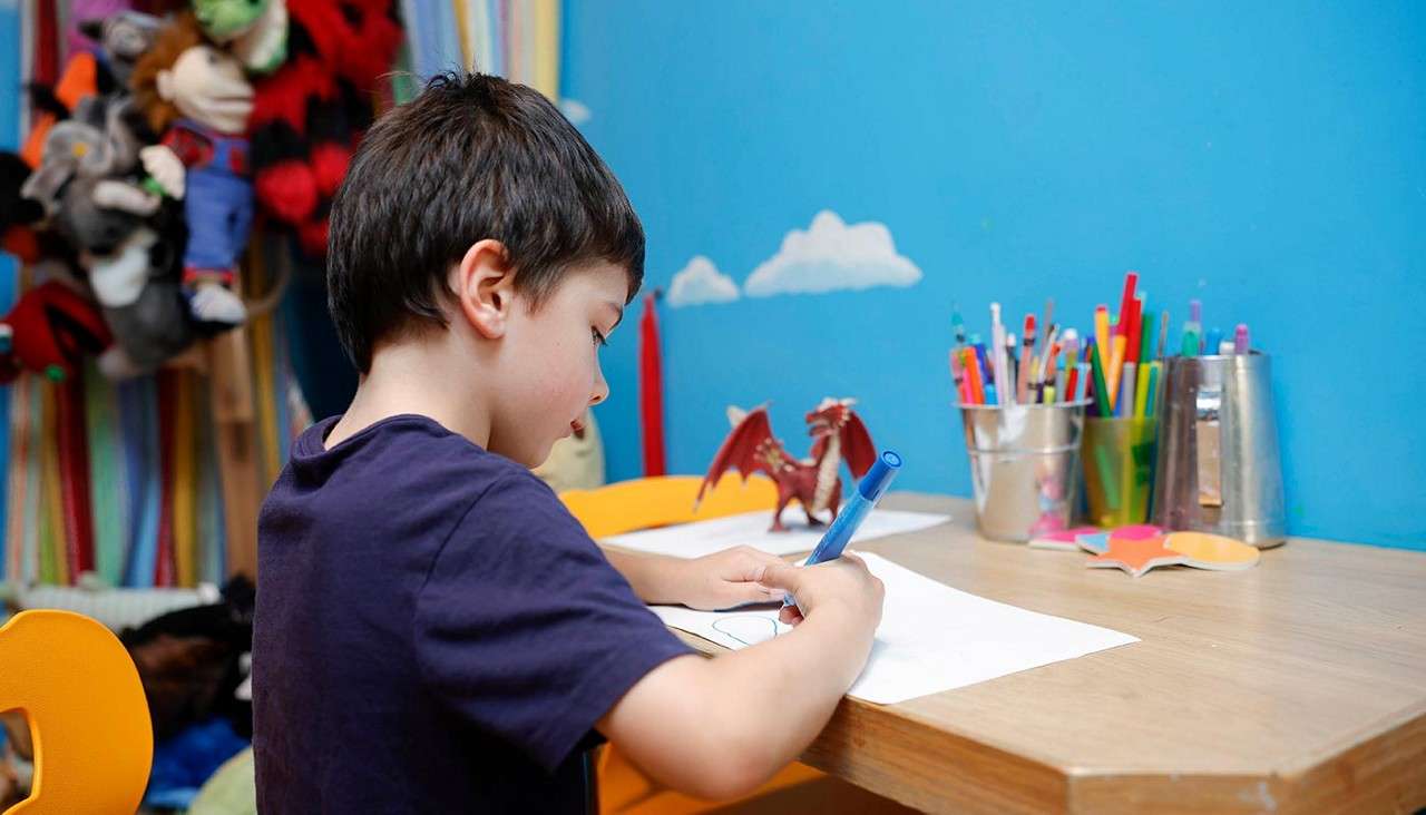 A little boy sat drawing a picture. 