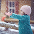 Little girl wearing green coat and pink hat and scarf playing in the snow 