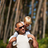 Child on fathers shoulders walking through the forest