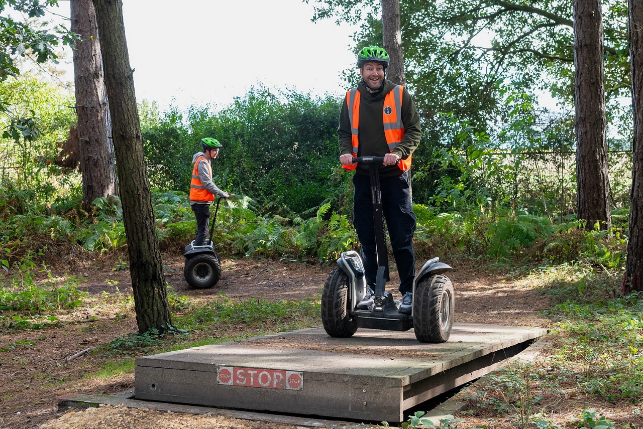 Two adults riding segways through the forest 