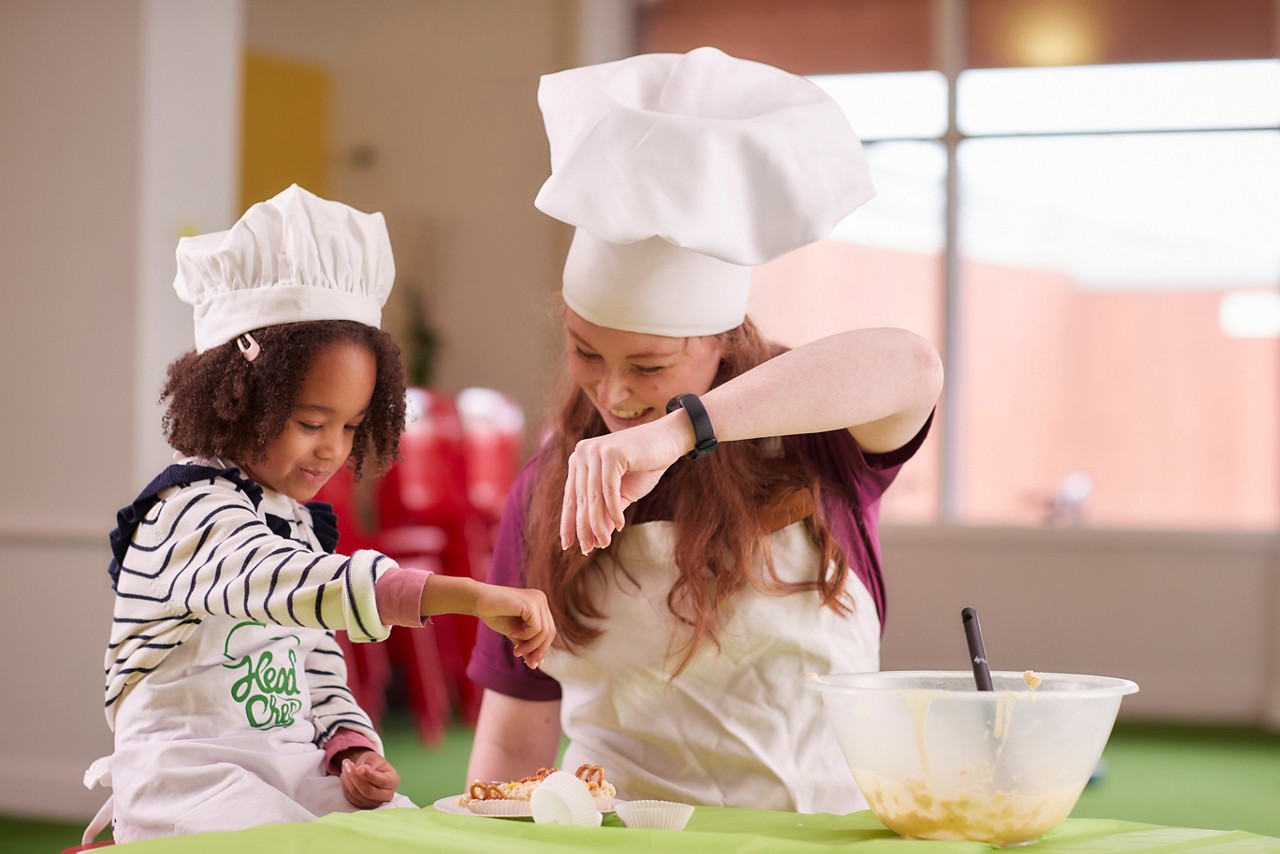 Young girl with an adult creating and decorating chocolate treats.