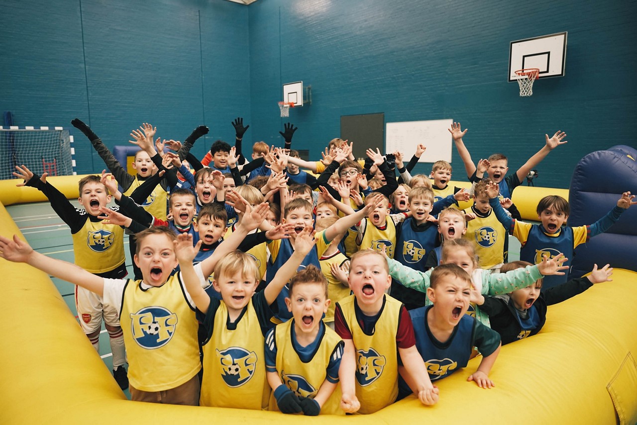 Group of children cheering as they play football.
