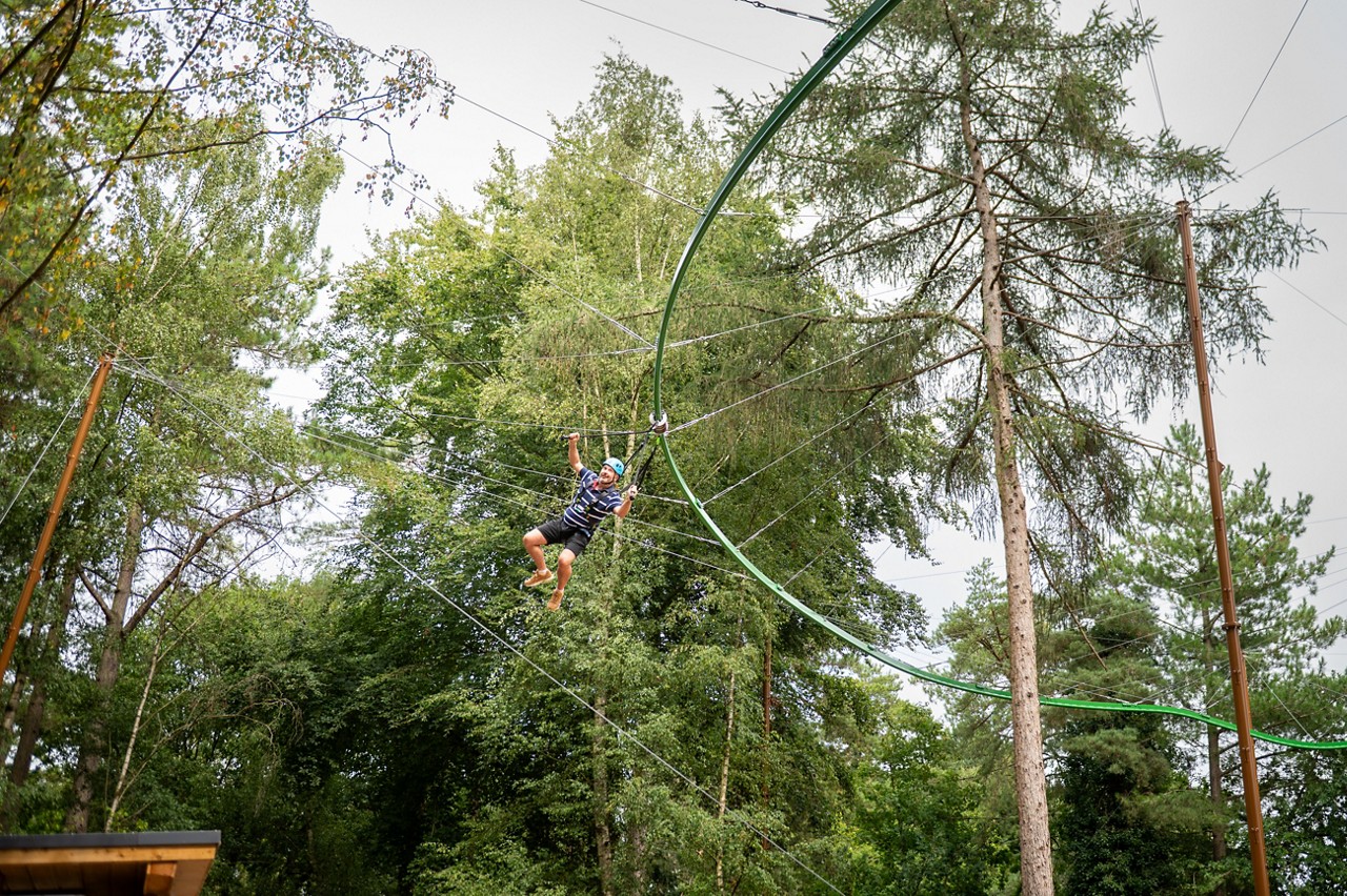 Person suspendend from a track going through the treetops.