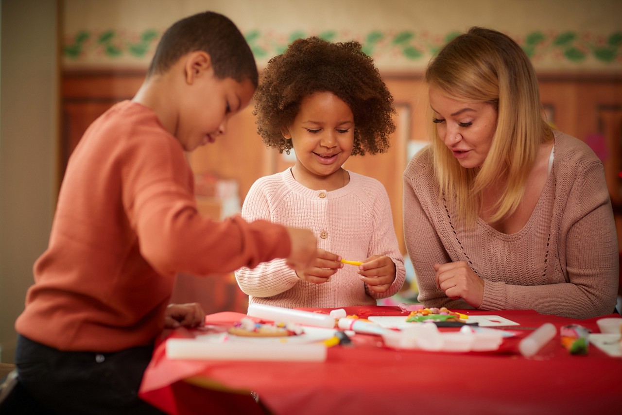 Young people decorating Christmas cookies with the help of an adult.