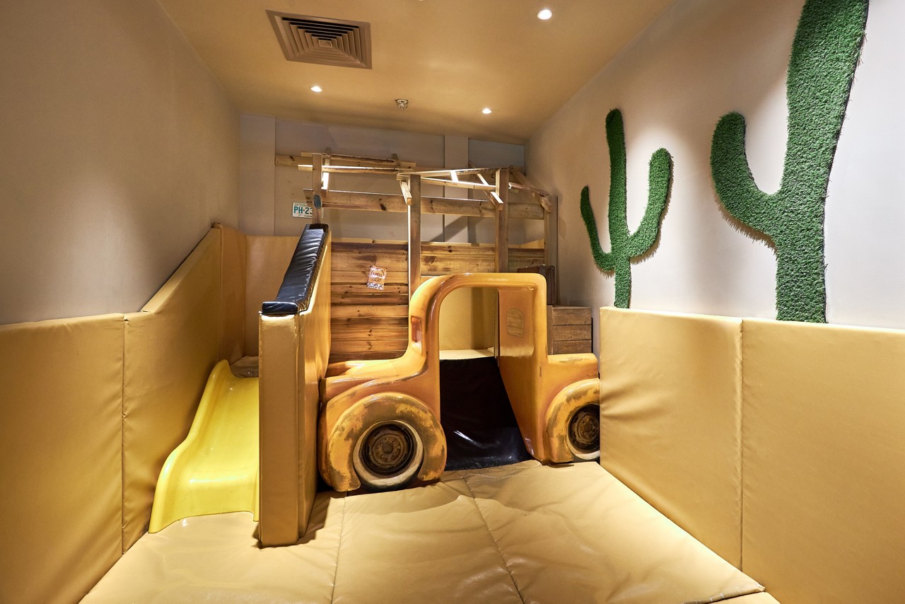 A little girl sat on her Dad's knee colouring in a picture at the table. 