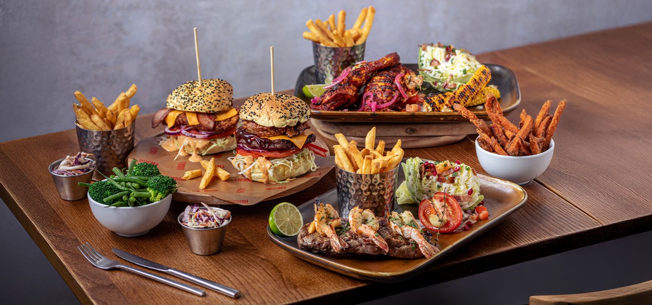 Table of food from the Huck's menu including, fries, loaded burgers and steak.