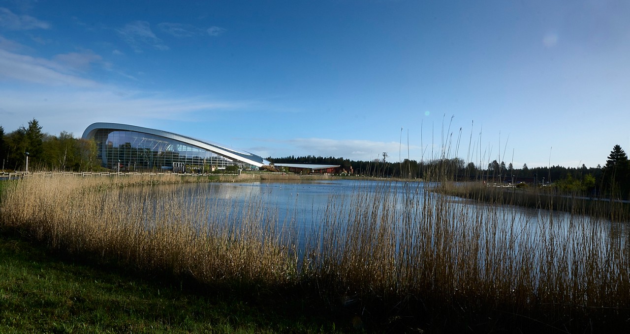 View of the lake with a curved building in the background.