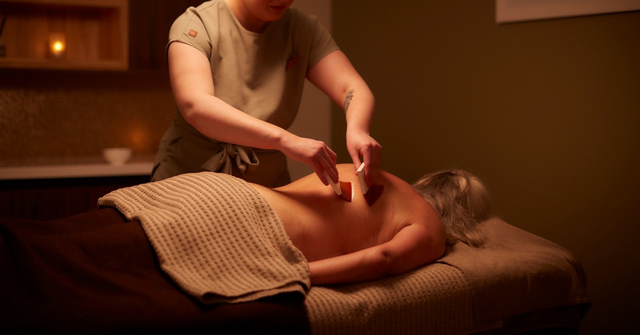 Woman having soft brushes stroked against her back.