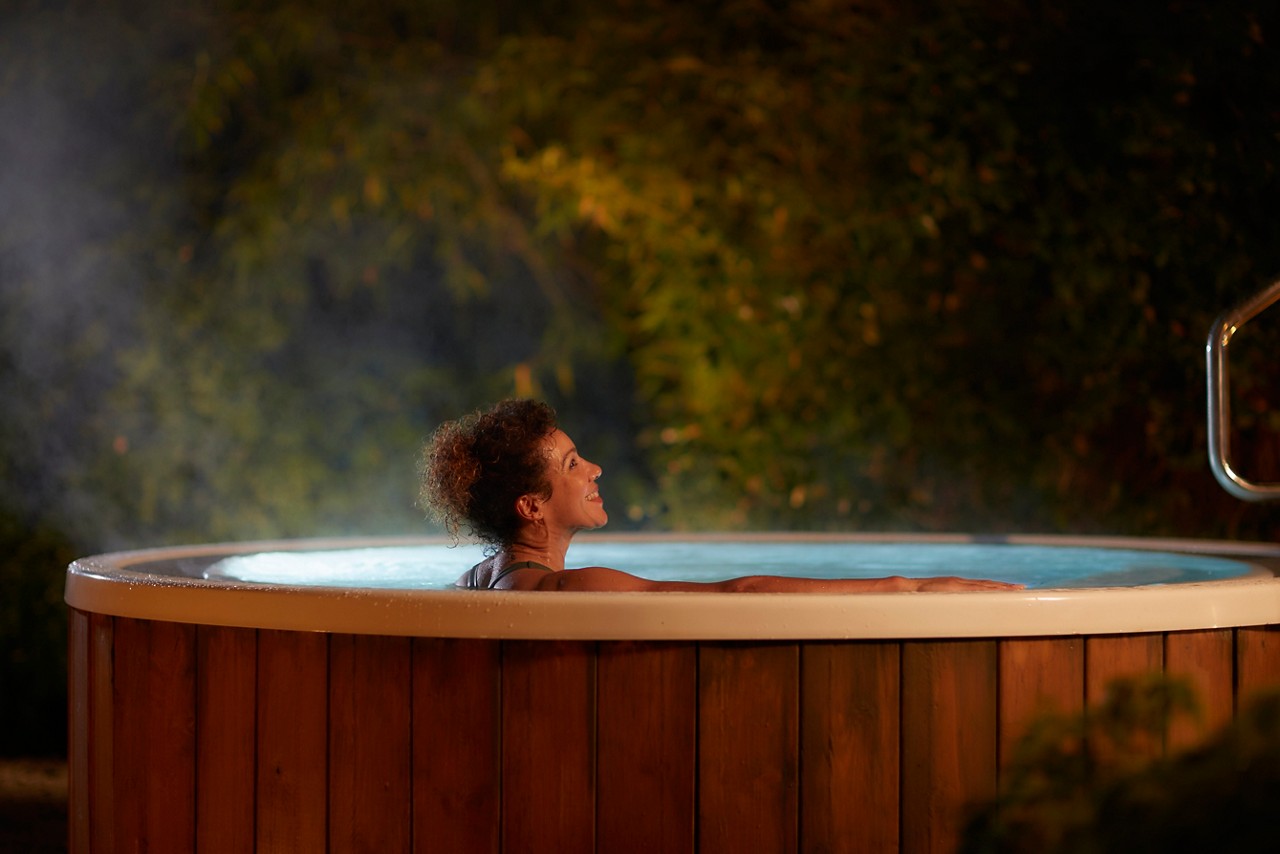 Woman soaking in a bubbling outdoor hot tub.