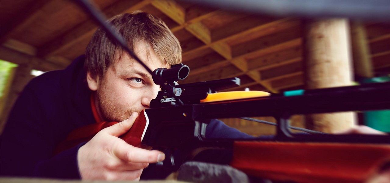 A man aiming down the sights of  a crossbow