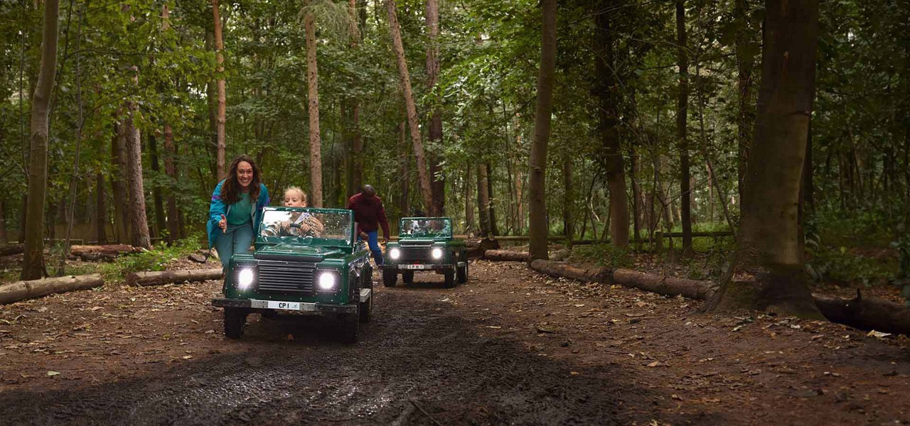 A girl in a mini car riding through the forest